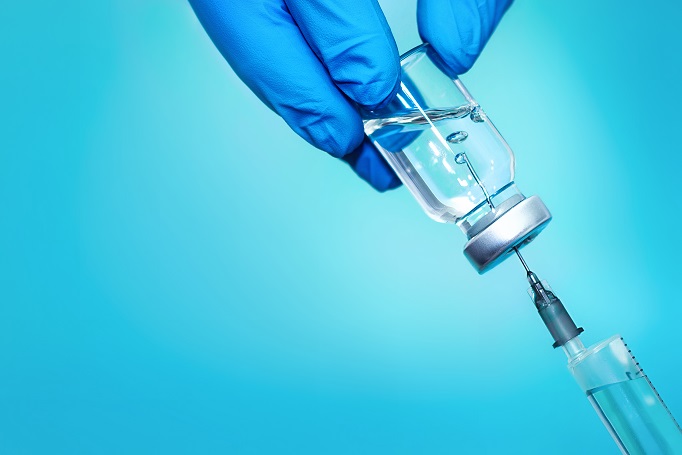 A Bottle with vaccine and syringe on a blue background.The concept of medicine, healthcare and science